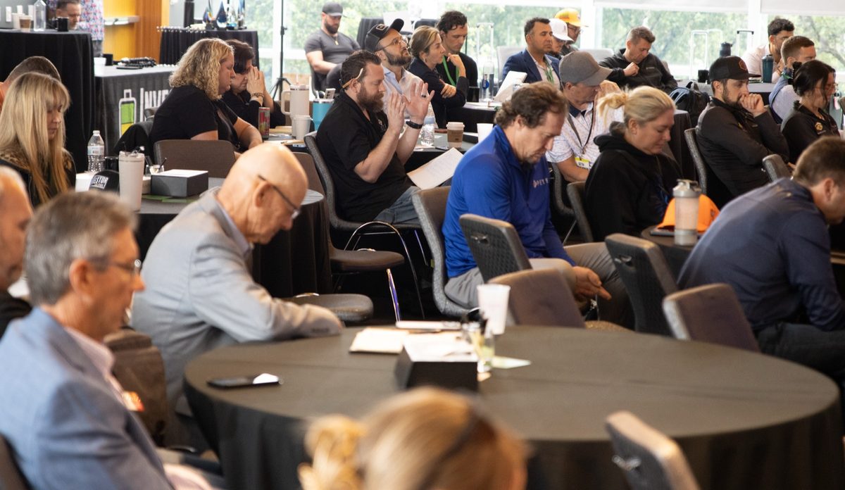 Members at round tables taking notes